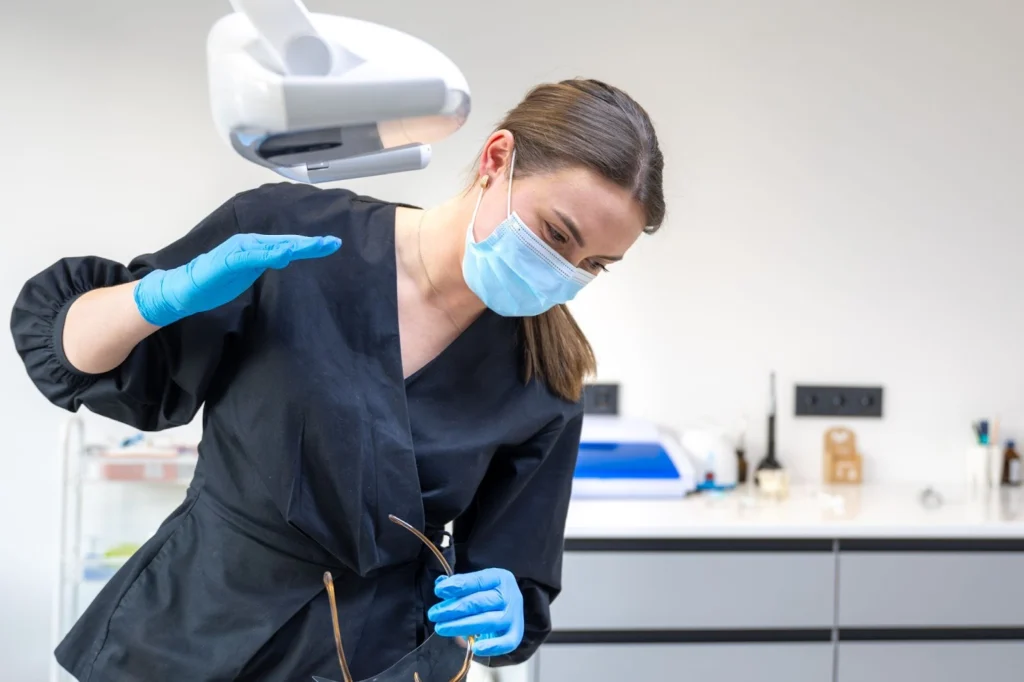 Млада зъболекарка в дентална клиника се подготвя за лечение на пациент.